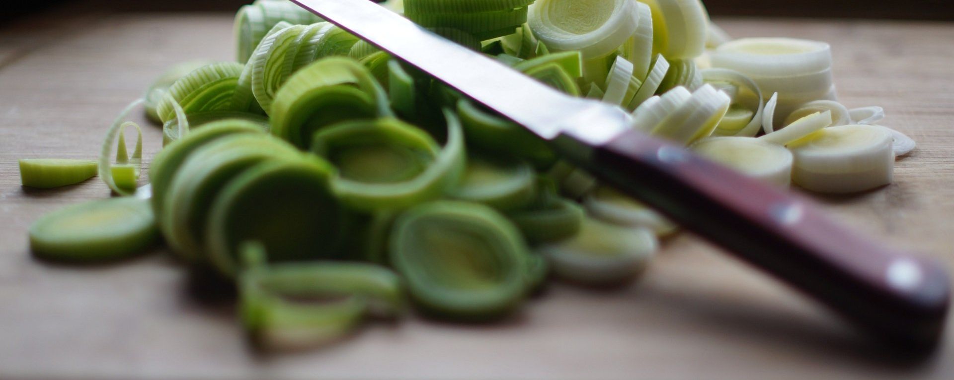 Vegitables being cut on a wooden cutting board