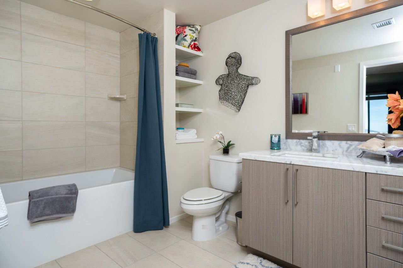 Bathroom in an apartment with a tub/shower, toilet, and wooden vanity.