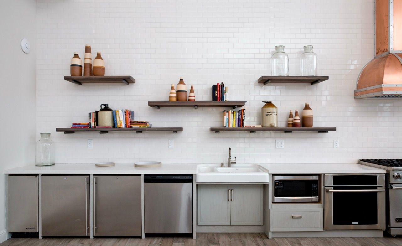 Modern kitchen with white subway tile backsplash, stainless appliances, and open wooden shelves.