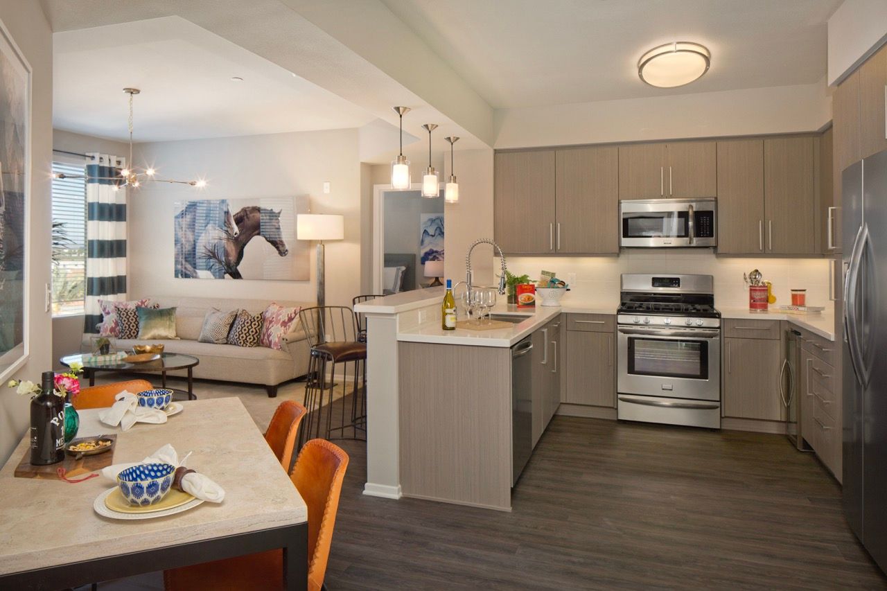 Open-concept kitchen and living area in a modern apartment with stainless steel appliances.