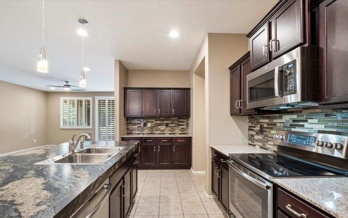 Kitchen with dark brown cabinets, stainless steel appliances, and granite countertops.