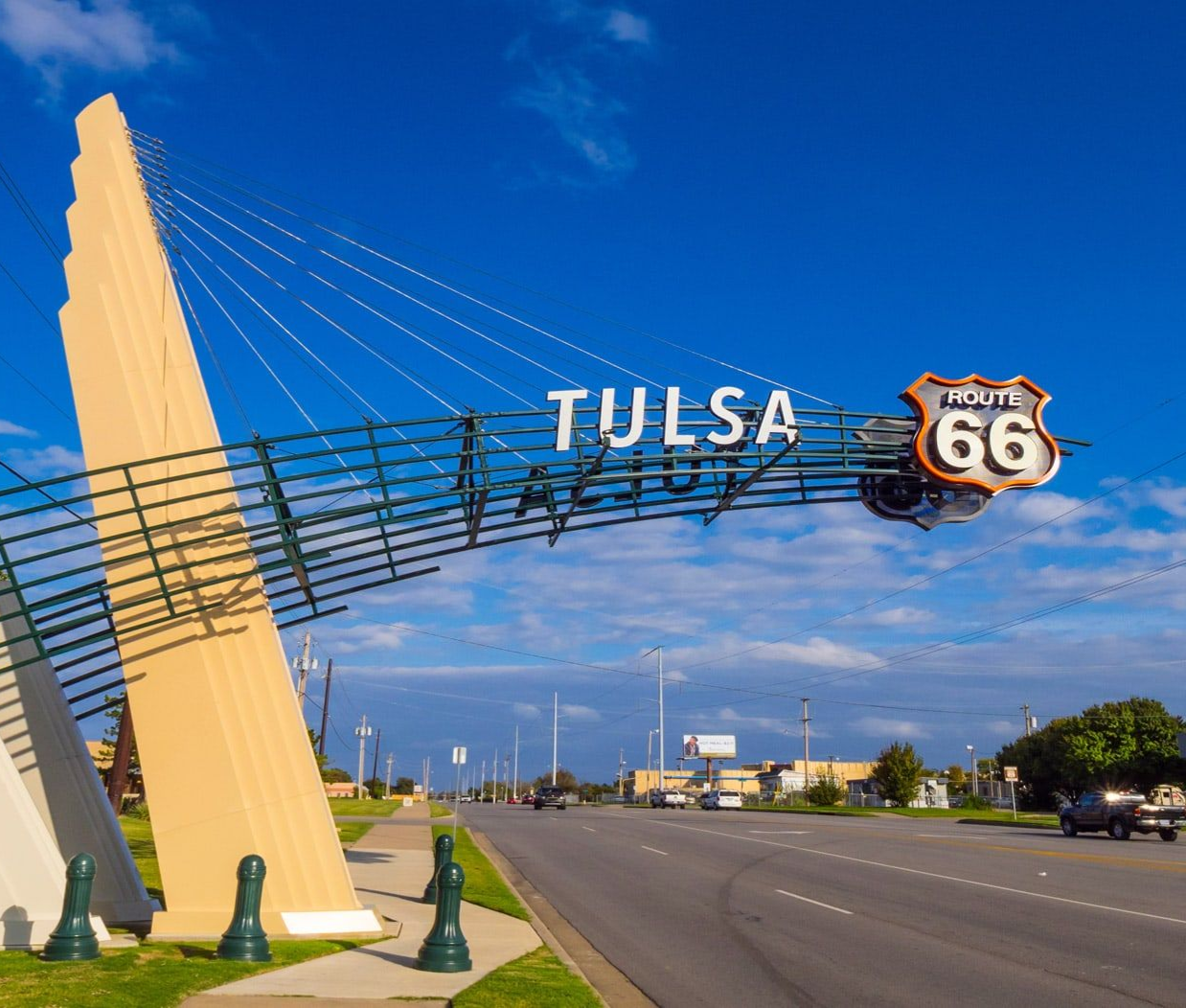 The Route 66 Rising sculpture in Tulsa, Oklahoma, features a large, stylized arch over a road against a blue sky.