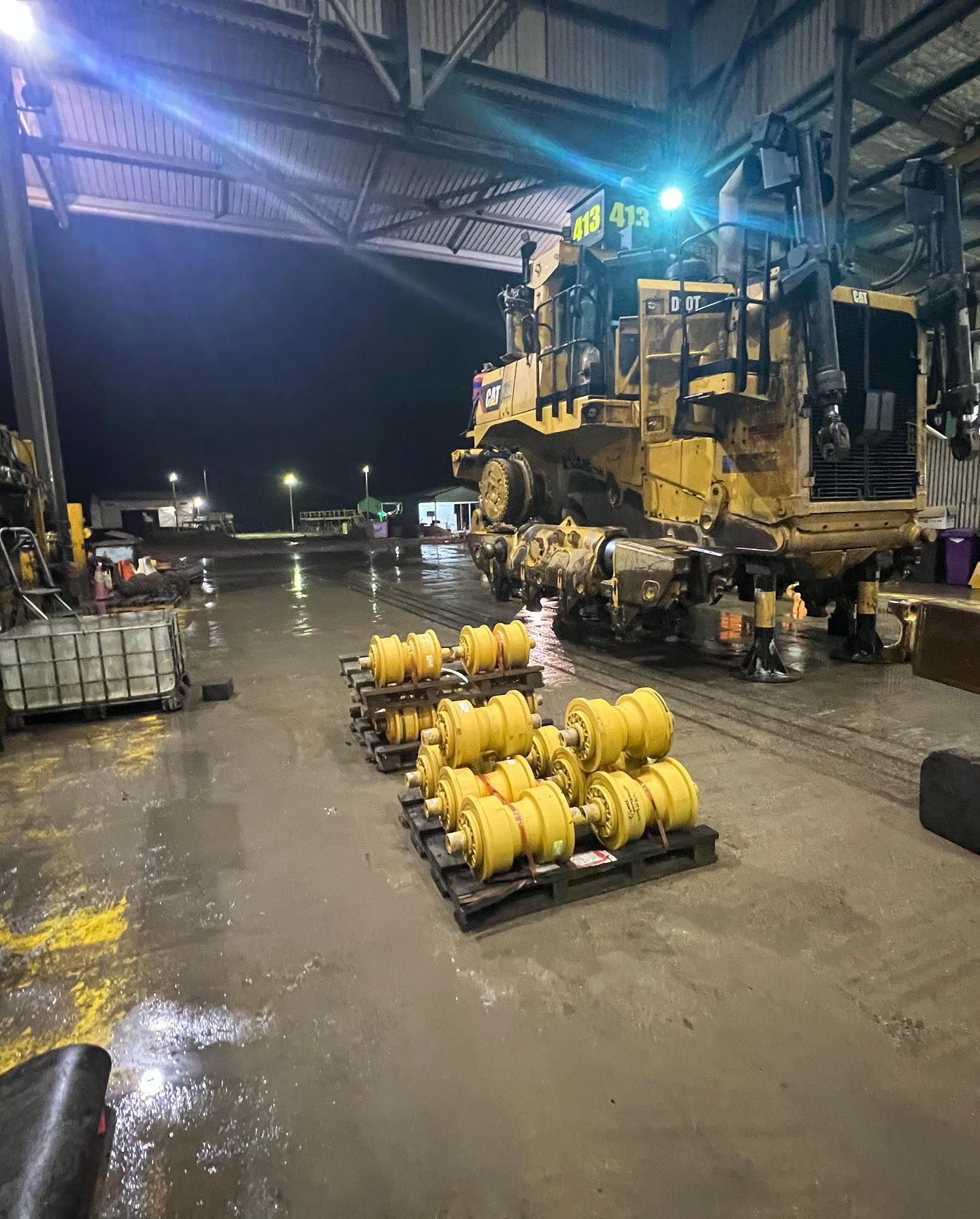 Yellow Heavy Machinery and Spare Parts in a Wet Industrial Setting at Night — HOLESHOT Diesel In Blackwater, QLD