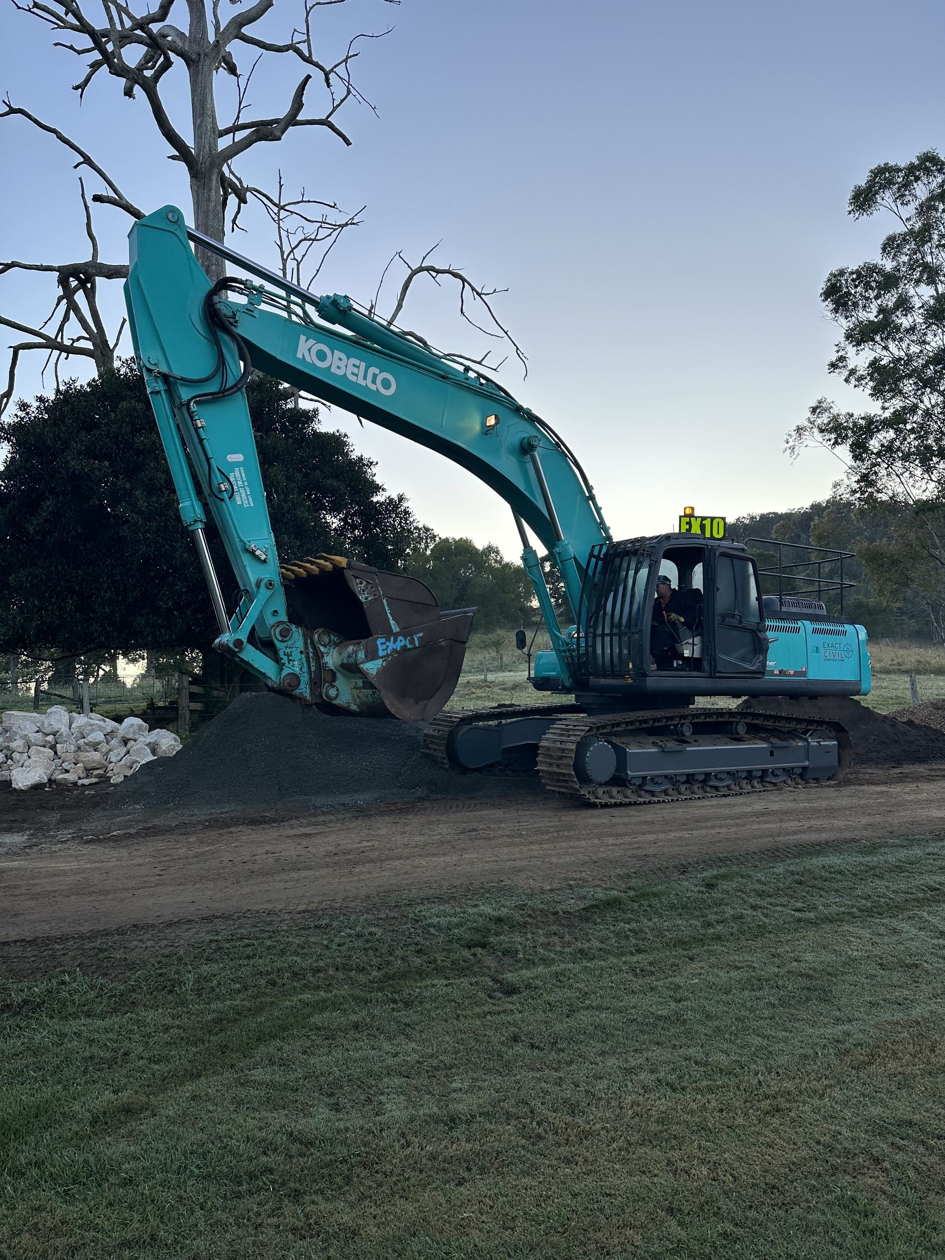 Teal Excavator Dumping Gravel on a Lawn — HOLESHOT Diesel In Brisbane, QLD