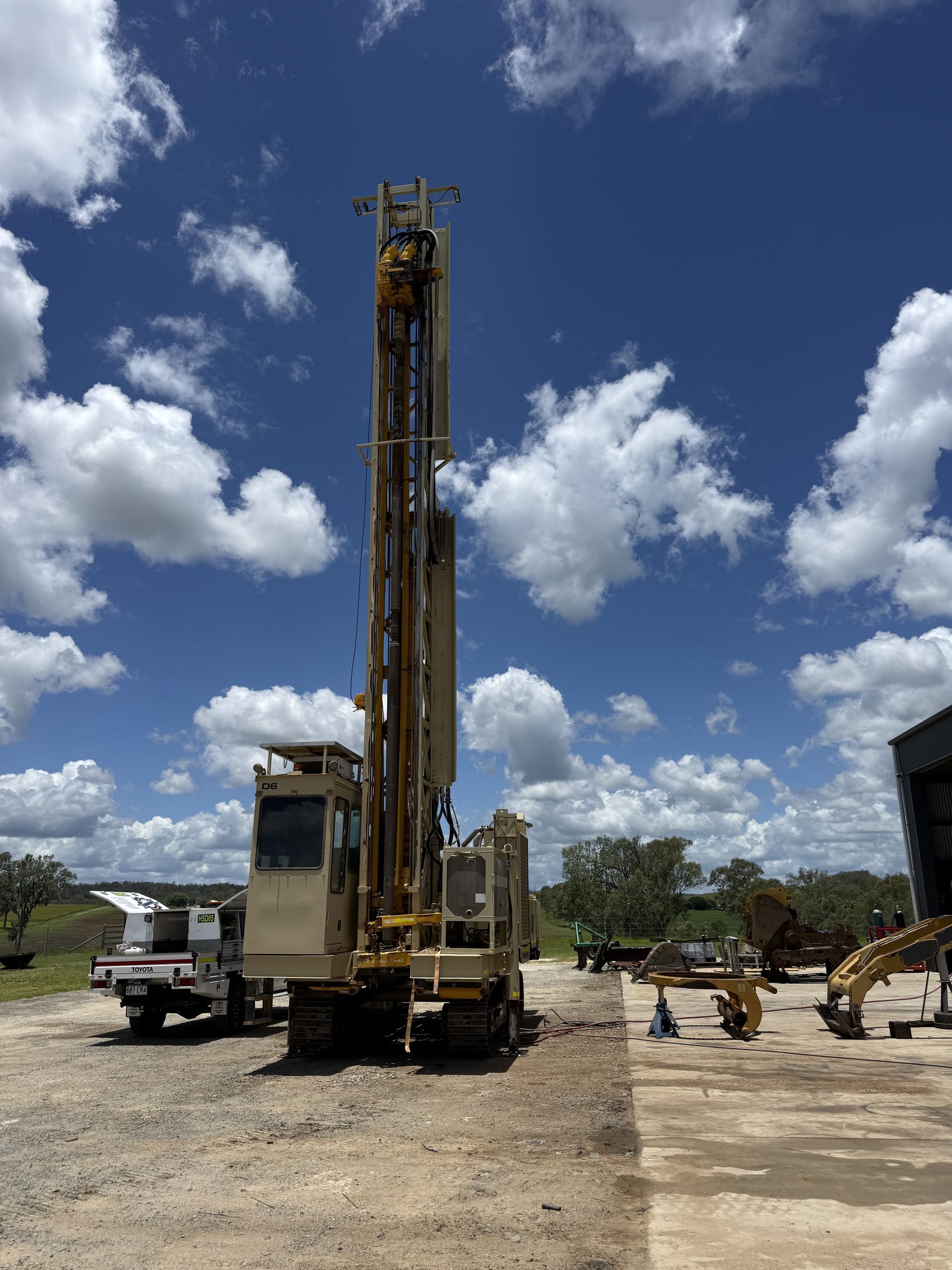 Yellow Drilling Rig Under a Blue Sky With Puffy White Clouds, on a Construction Site — HOLESHOT Diesel In Brisbane, QLD