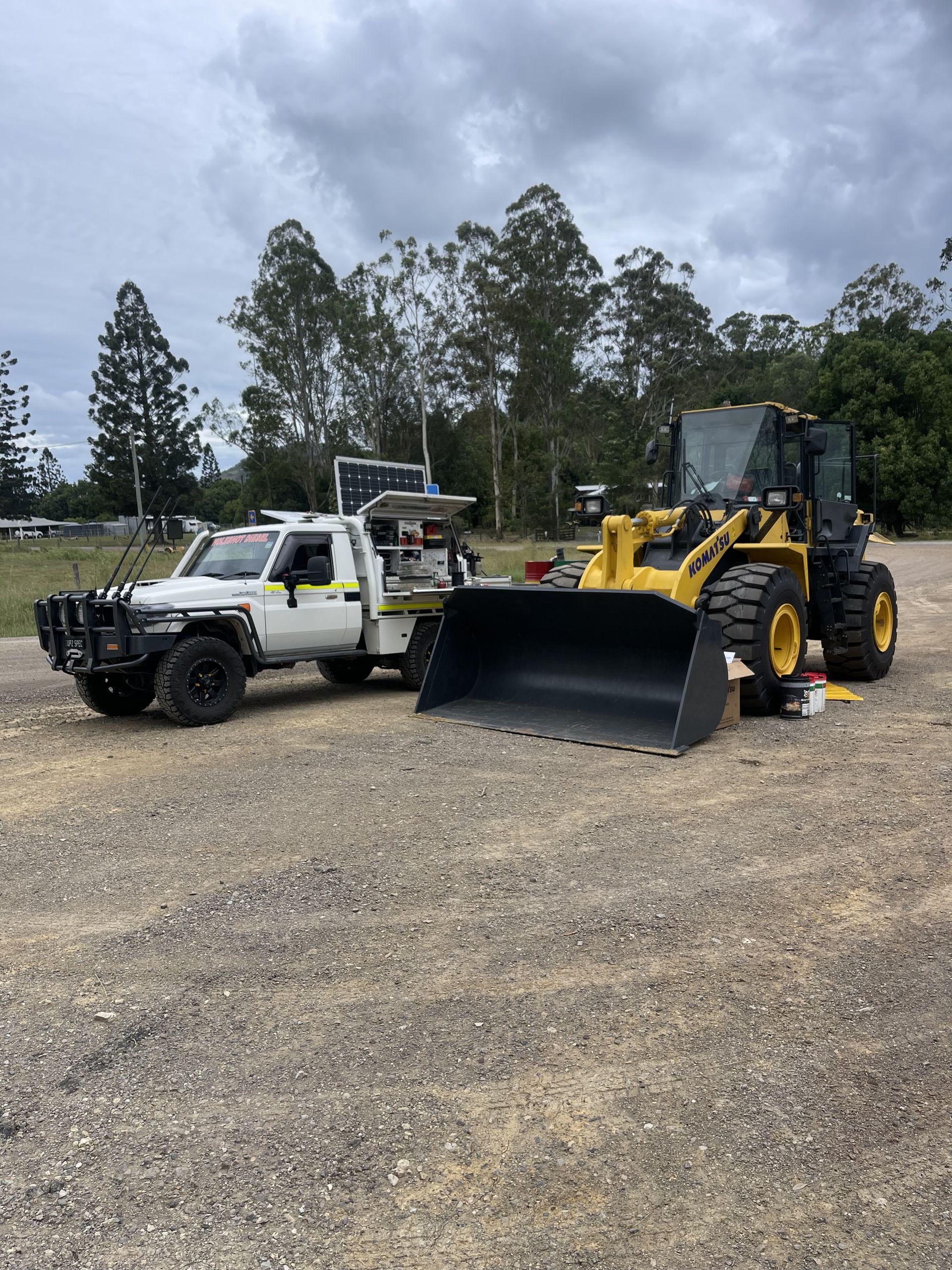 White Truck Next to a Yellow Front-end Loader on Gravel — HOLESHOT Diesel In Miles, QLD