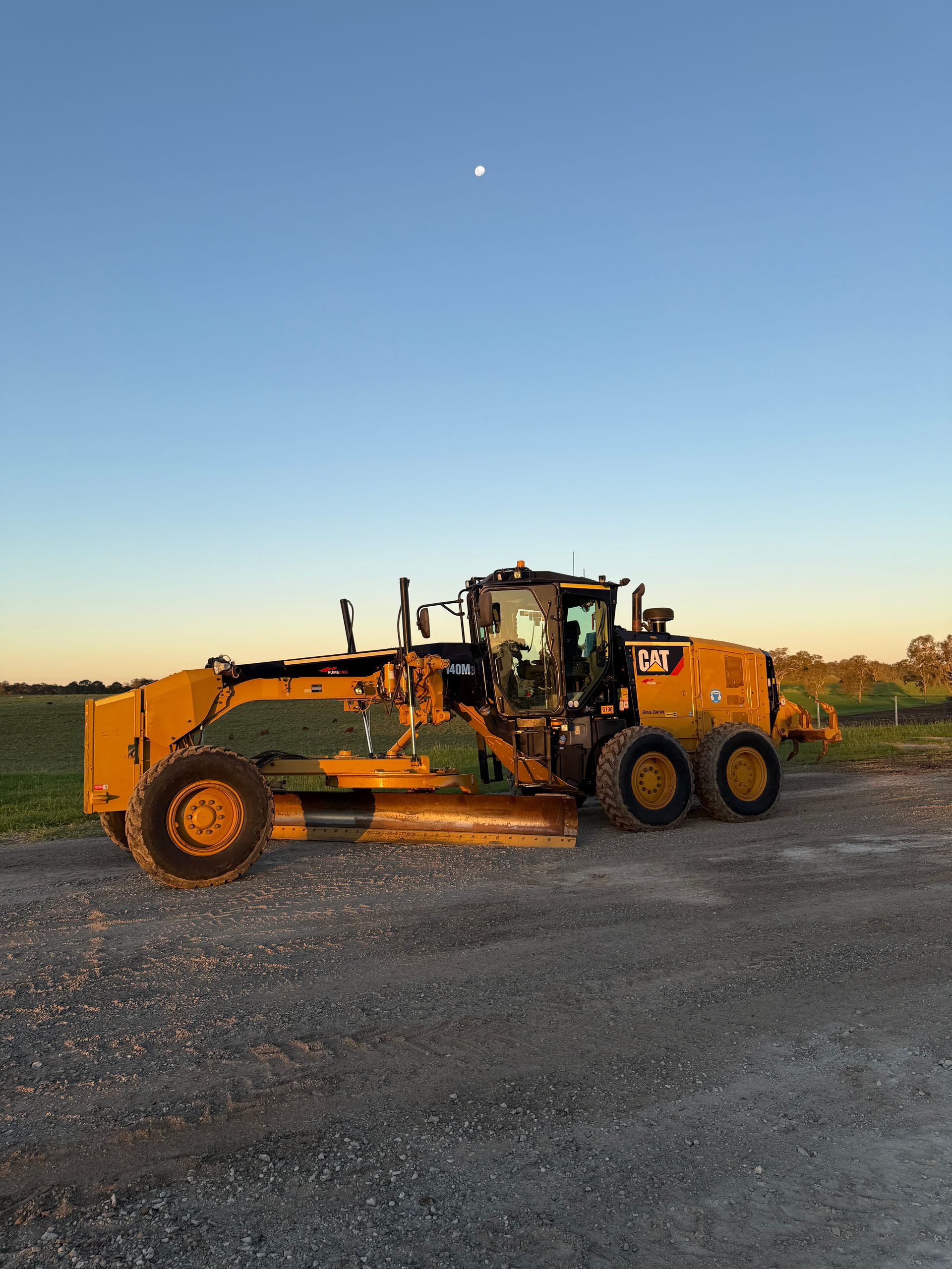 Yellow Caterpillar Grader on Gravel, Under a Blue Sky at Dusk — HOLESHOT Diesel In Roma, QLD