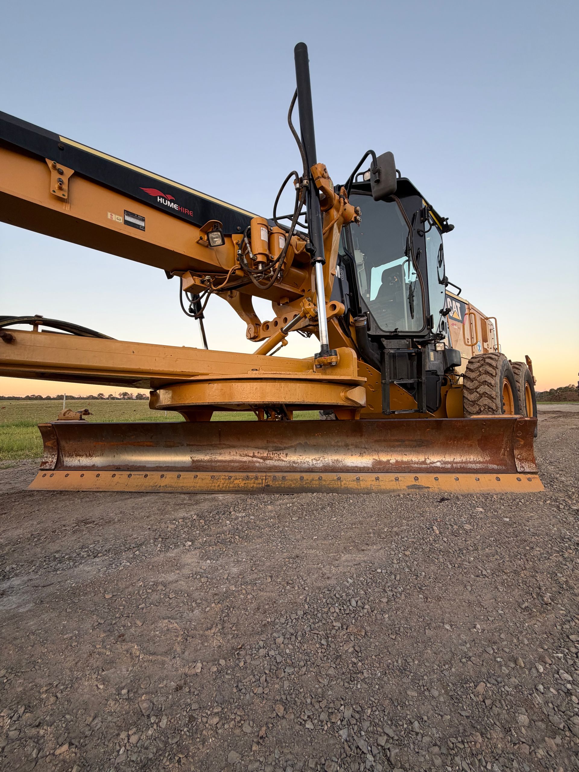 Yellow Motor Grader on Gravel in a Field at Sunset — HOLESHOT Diesel In Gympie, QLD
