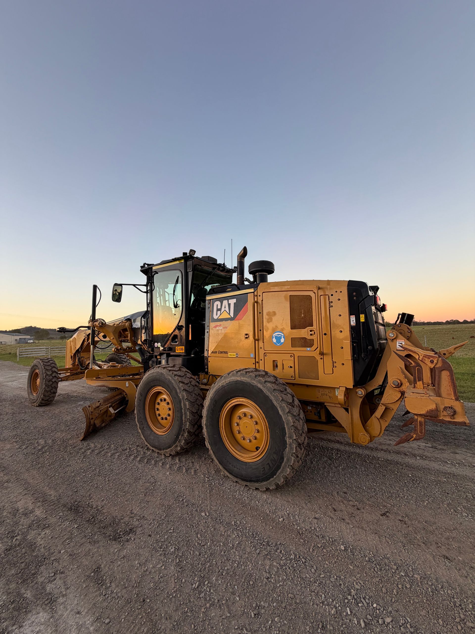 Yellow Caterpillar Grader on Gravel Road, Blue Sky — HOLESHOT Diesel In Maryborough, QLD
