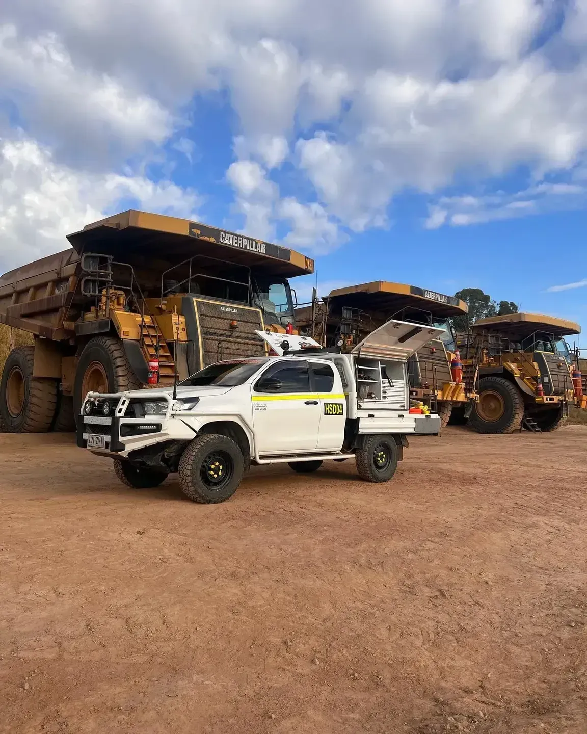 White Utility Truck Parked in Front of Large Mining Trucks on a Dusty Lot — HOLESHOT Diesel In Bundaberg, QLD
