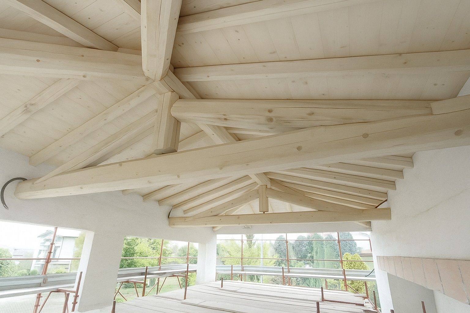 Travi del tetto in legno dipinte di bianco all'interno di un edificio in costruzione.
