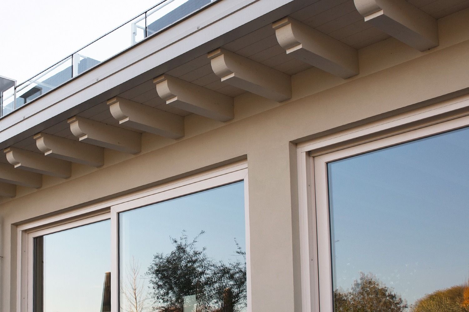 Esterno dell'edificio con infissi bianchi e travi decorative in legno sotto il tetto.