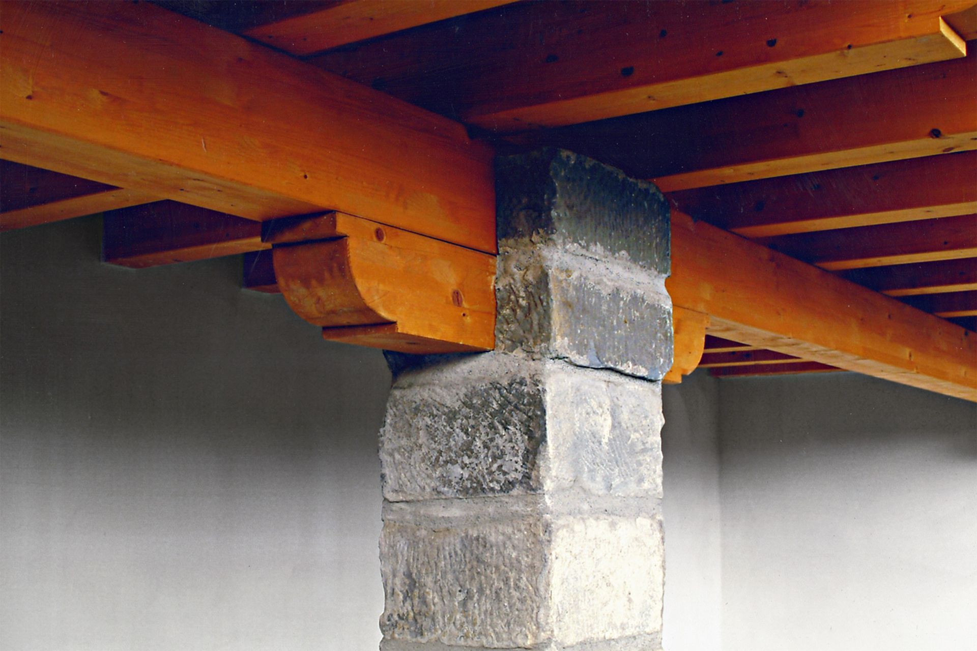 Travi di legno sostenute da un pilastro di pietra all'interno di un edificio.