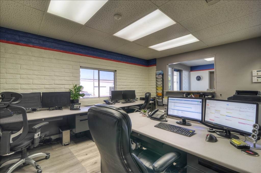 A room with a lot of computers on the desks and chairs.