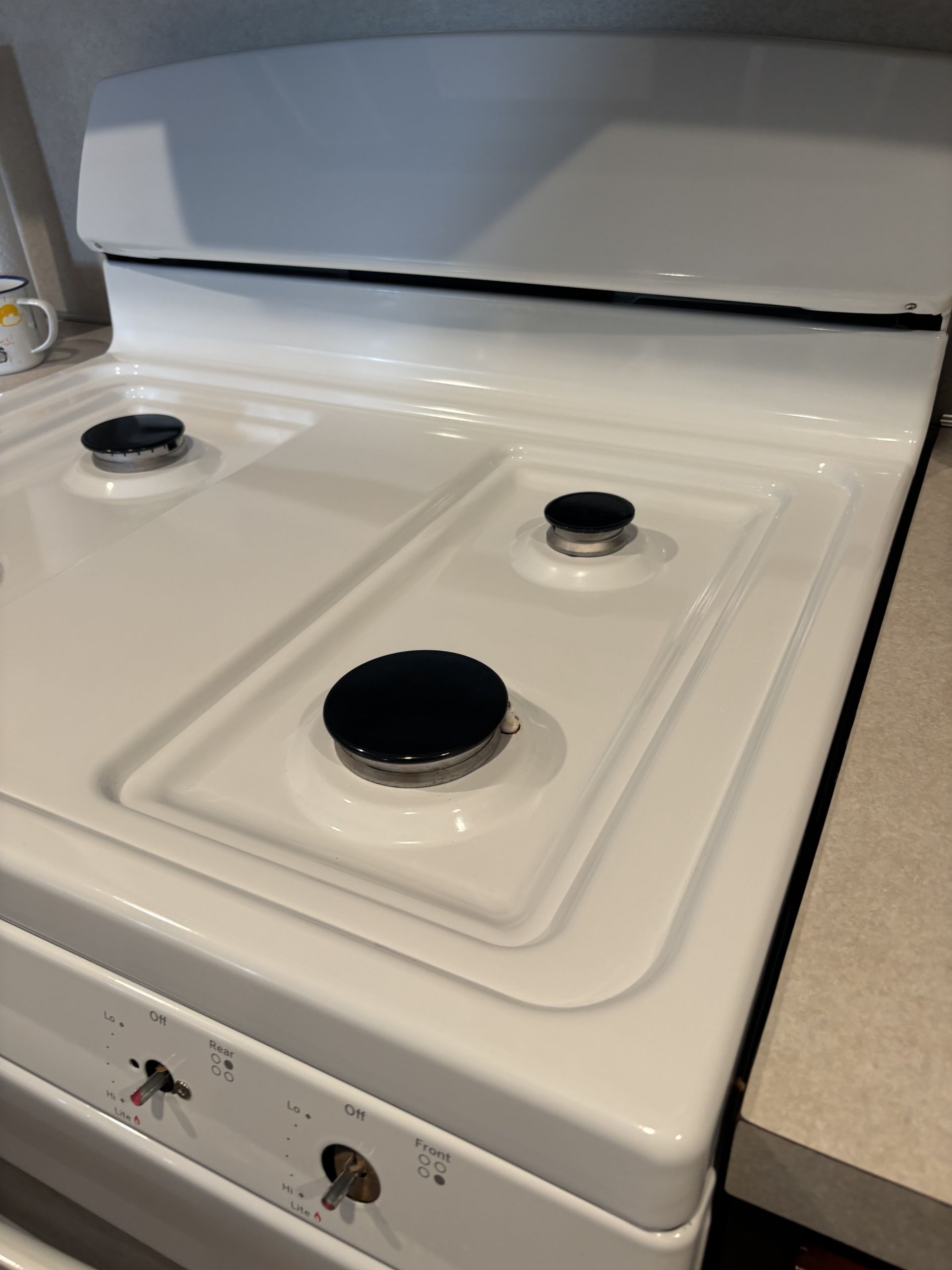 White gas stovetop with four black burners.