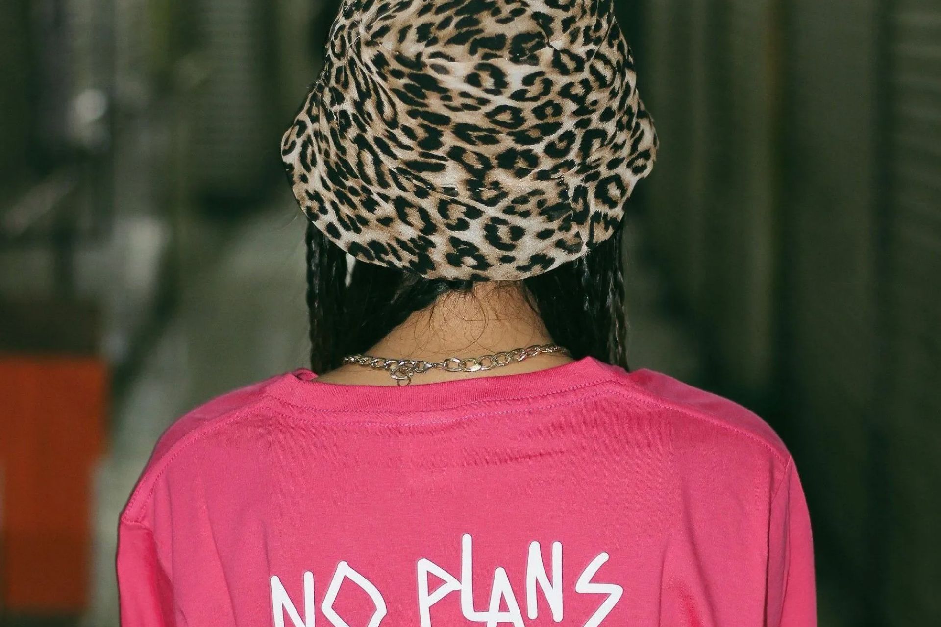 A woman wearing a leopard print hat and a pink shirt with the words `` no plans '' on the back.