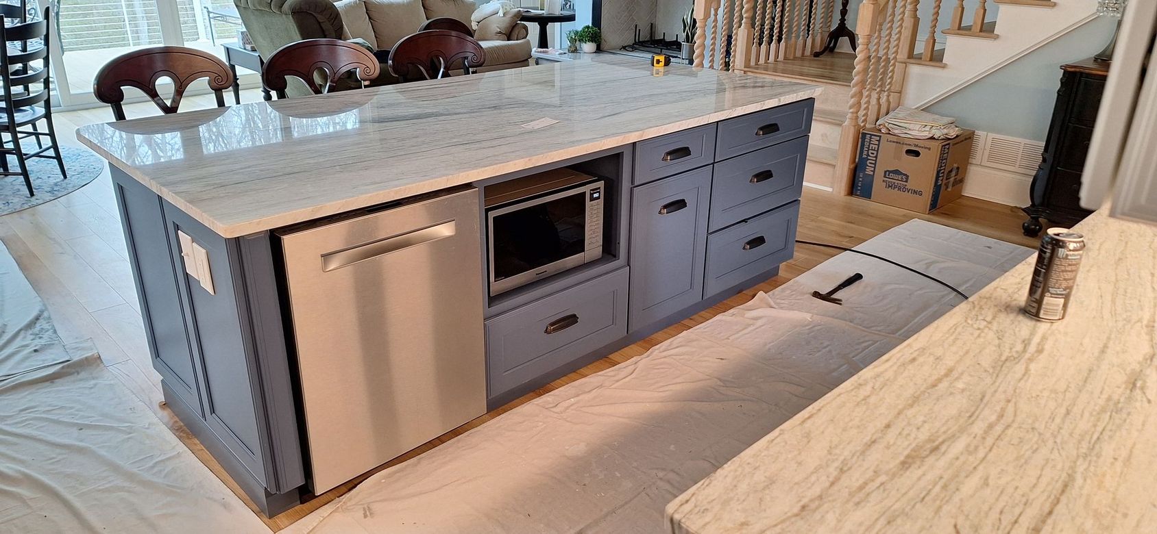 A kitchen island with a microwave and a dishwasher in a living room.