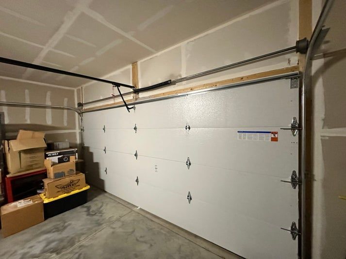 Garage interior with closed white door, exposed framing, and boxes.