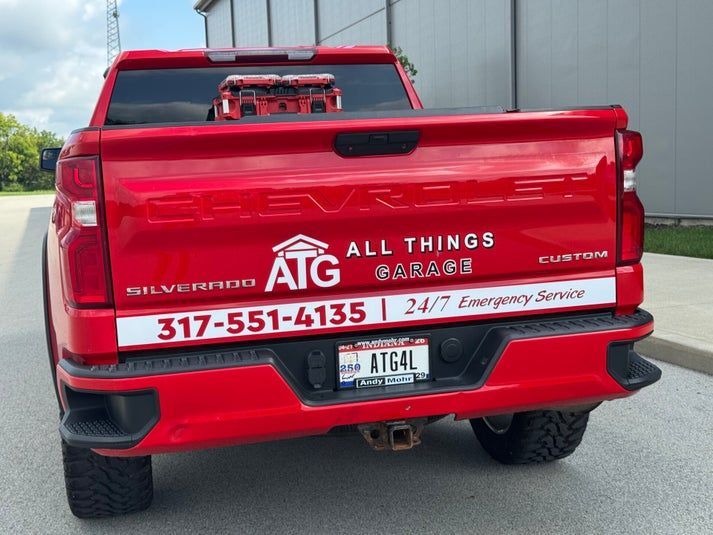 Red Chevrolet Silverado pickup truck with business logo.