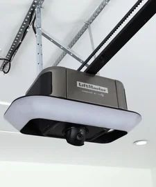 A LiftMaster garage door opener, silver and black, mounted on a white ceiling with attached track and camera.
