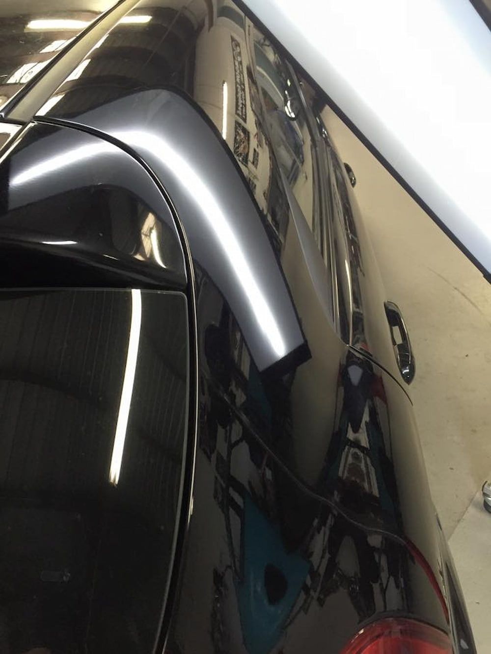 A Black Car is Parked in a Garage With a Reflection of Another Car — Rapid Auto Dent In Terrigal, NSW
