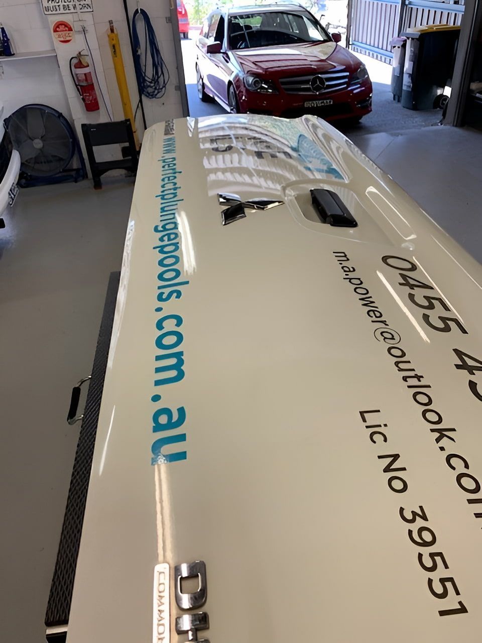 A Red Car Is Parked In A Garage Next To A White Van — Rapid Auto Dent In West Gosford, NSW