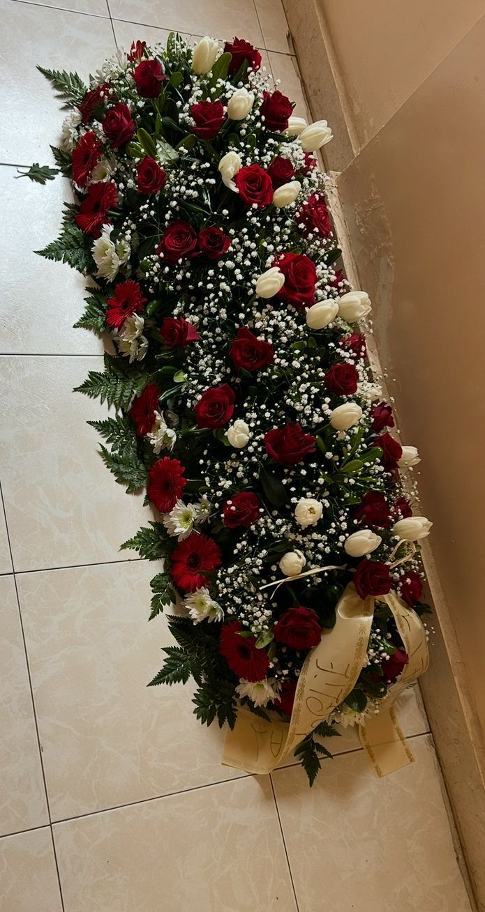 Primo piano di una colorata composizione floreale, che comprende orchidee bianche, gigli gialli e fiori selvatici viola.