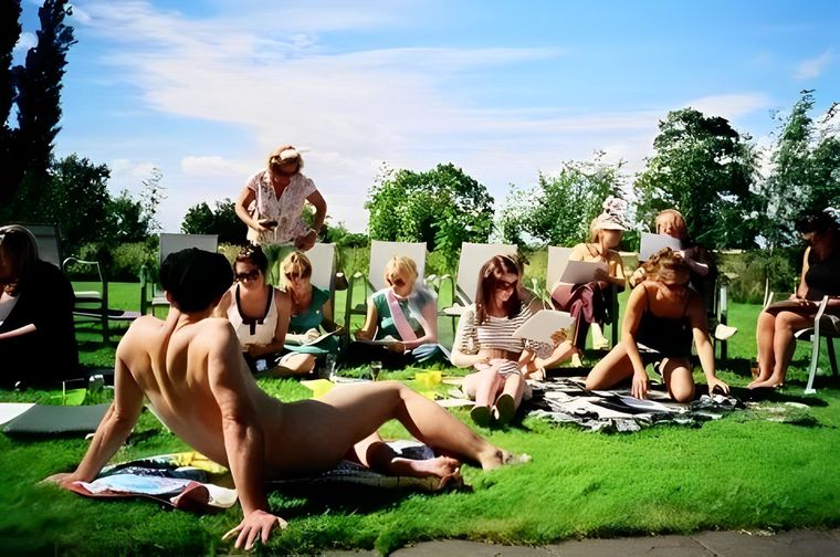 Male life model posing nude for a group of women