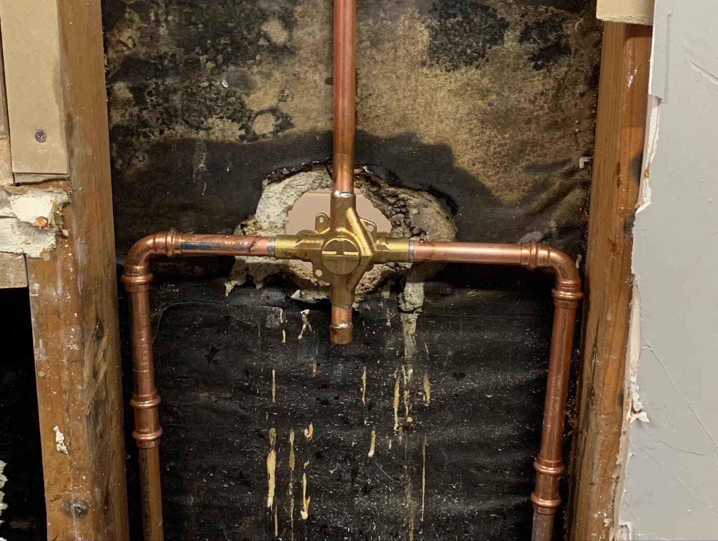 Copper shower valve and piping installed in a wall cavity.