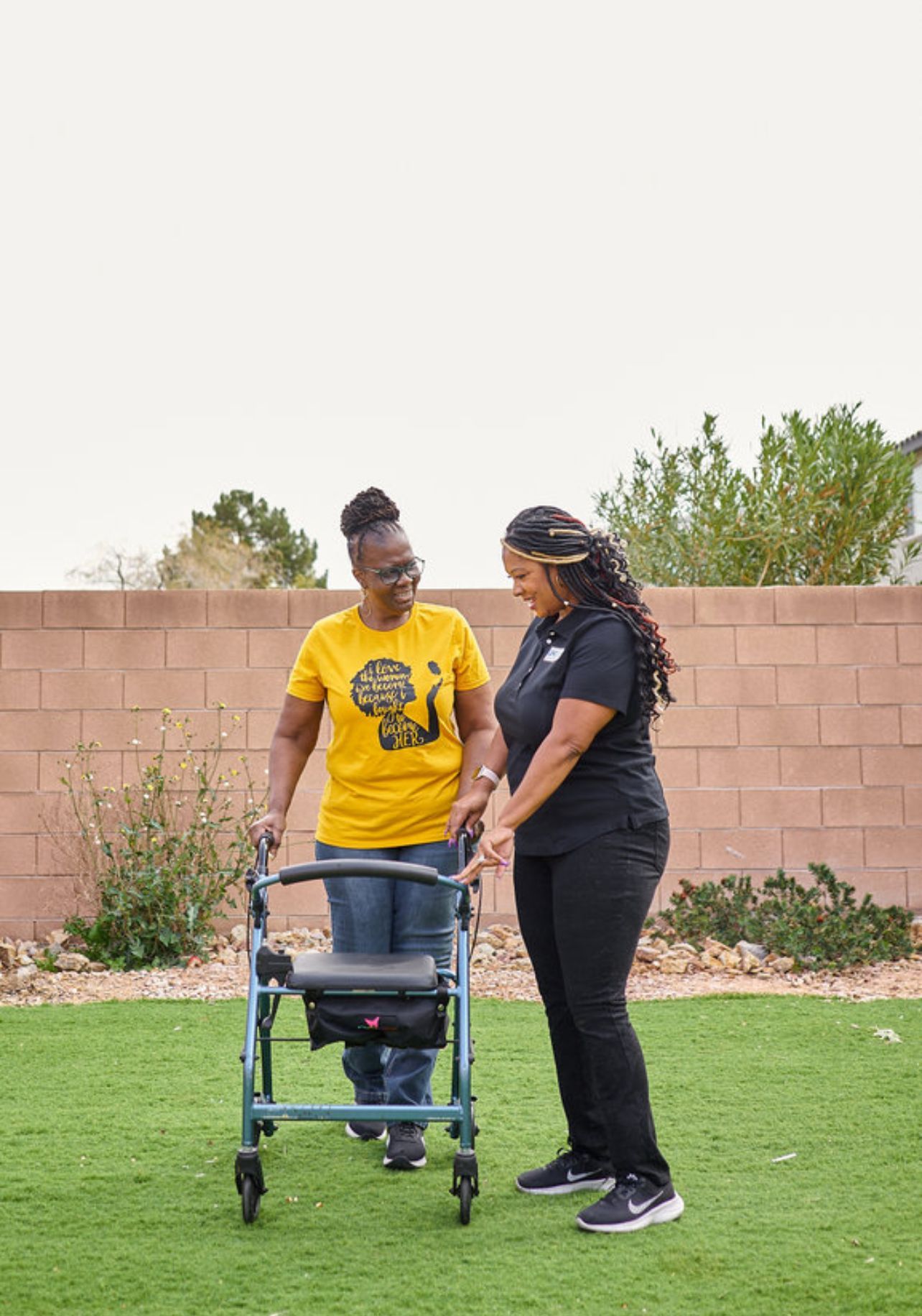 A nurse is standing next to an elderly woman holding a cane.