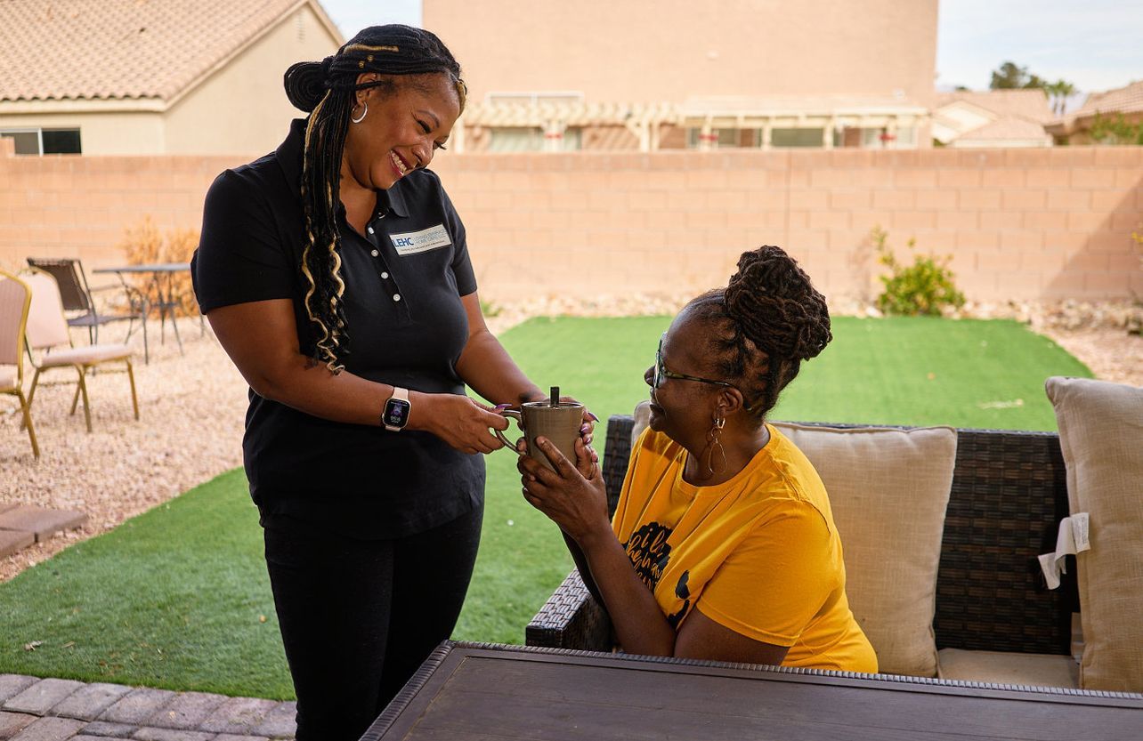 A woman is helping an older woman use a walker.
