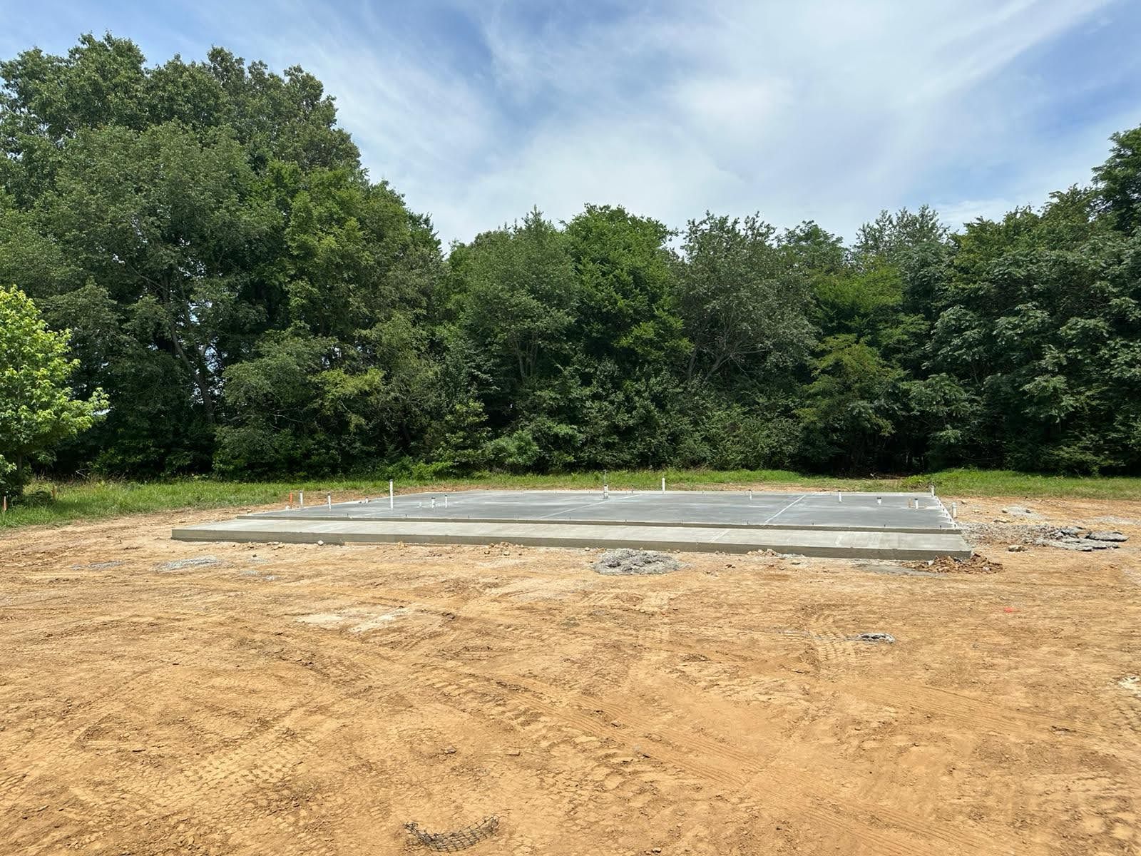 A concrete slab is sitting in the middle of a dirt field surrounded by trees.