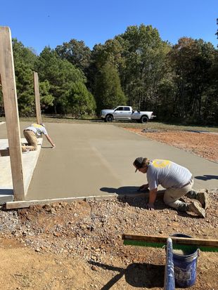 A couple of men are working on a concrete driveway.