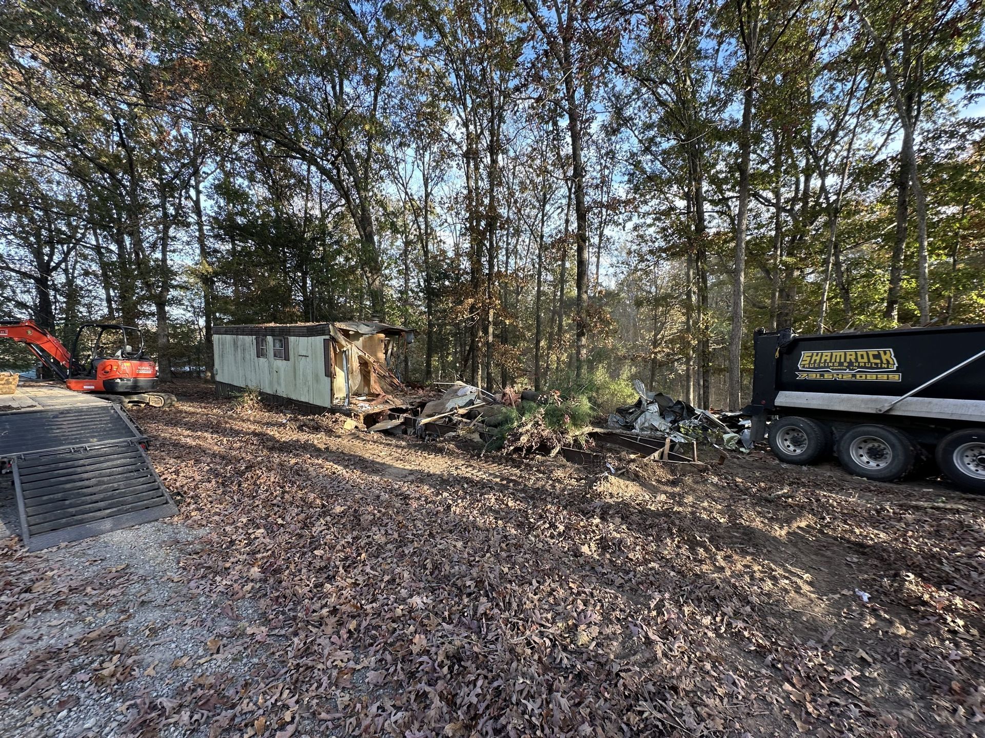 A dump truck is parked on the side of the road in the woods.