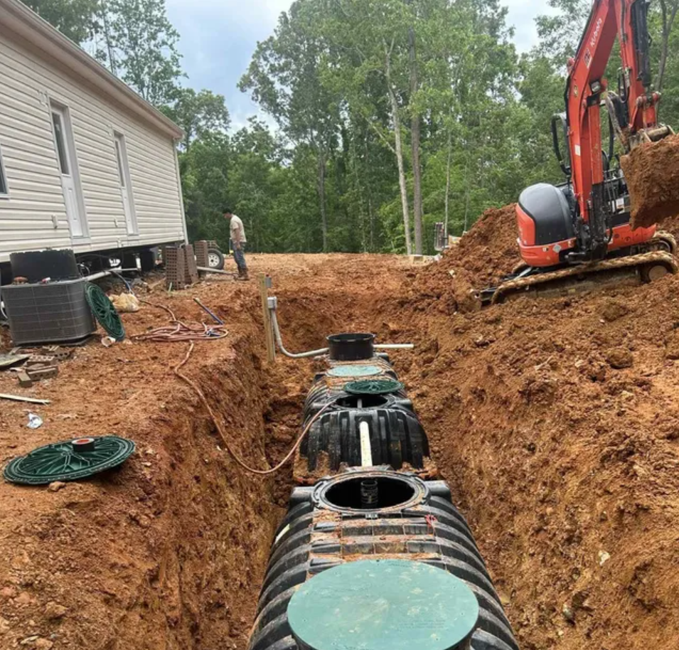 A septic tank is being installed in the dirt next to a house.