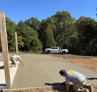 A couple of men are working on a concrete driveway.