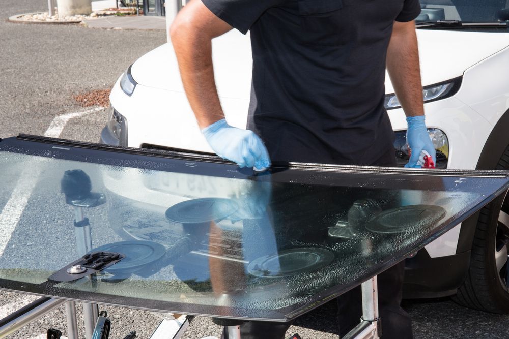 A Man Is Fixing A Windshield On A White Car — Windscreen Ambulance In Kawana, QLD