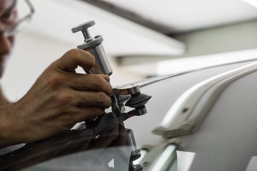 A Man Is Repairing A Windshield On A Car — Windscreen Ambulance In Kawana, QLD