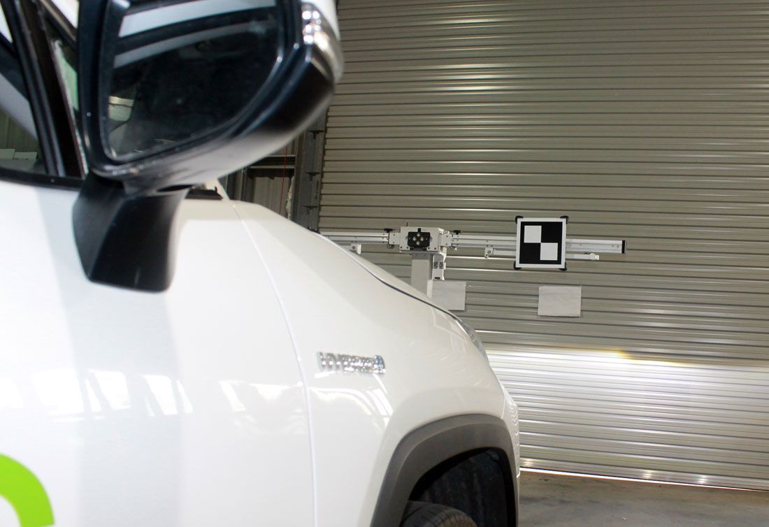 A White Car Is Parked In A Garage Next To A Checkered Sign — Windscreen Ambulance In Kawana, QLD