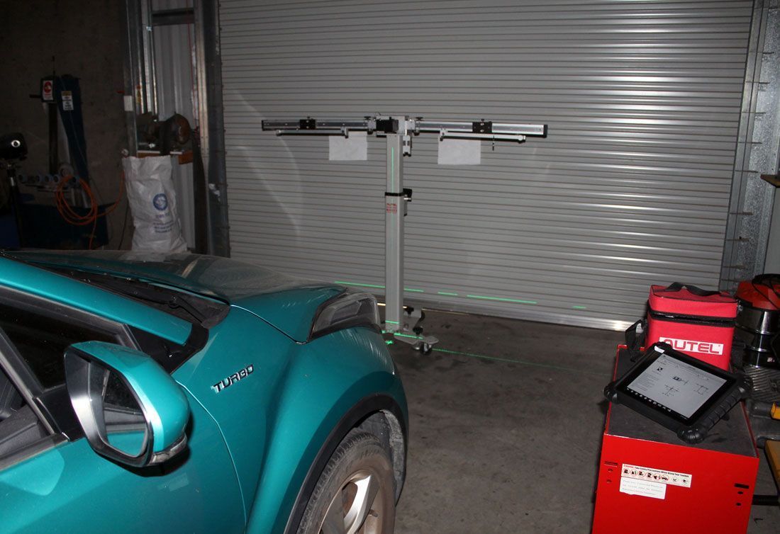 A White Car Is Parked In A Garage Next To A Checkered Sign — Windscreen Ambulance In Kawana, QLD
