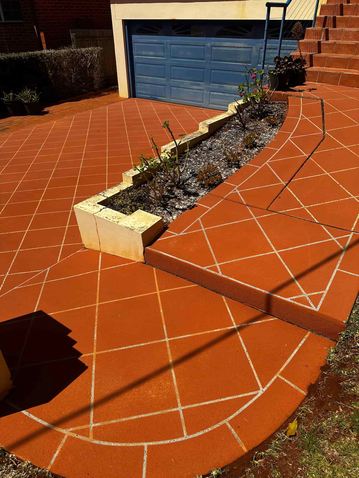 A Brick Walkway With a Blue Garage Door in the Background — Lighthouse pressure washing in Thrumster, NSW