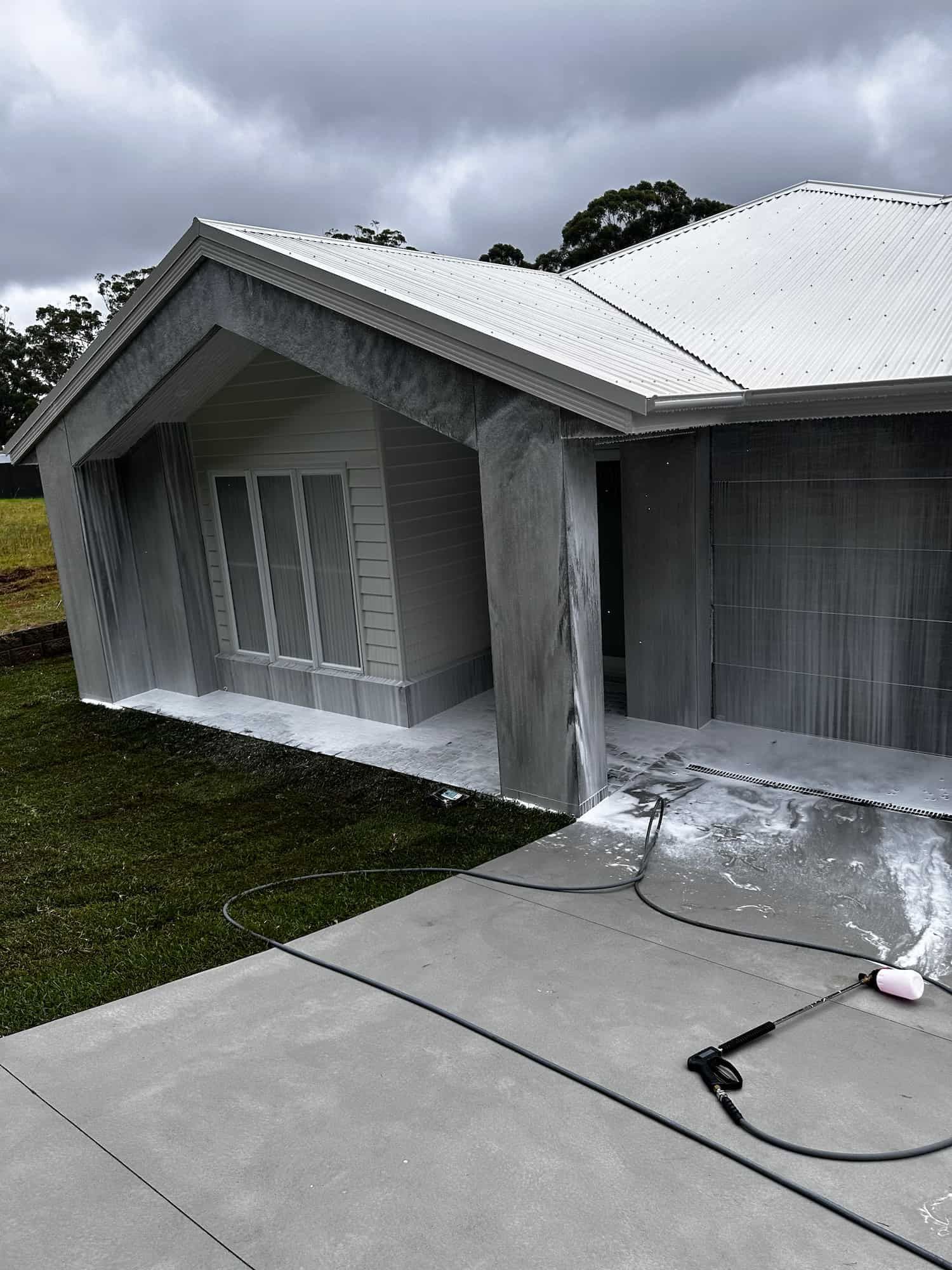 A House is Being Painted White With a High Pressure Washer — Lighthouse pressure washing in Bonny Hills, NSW