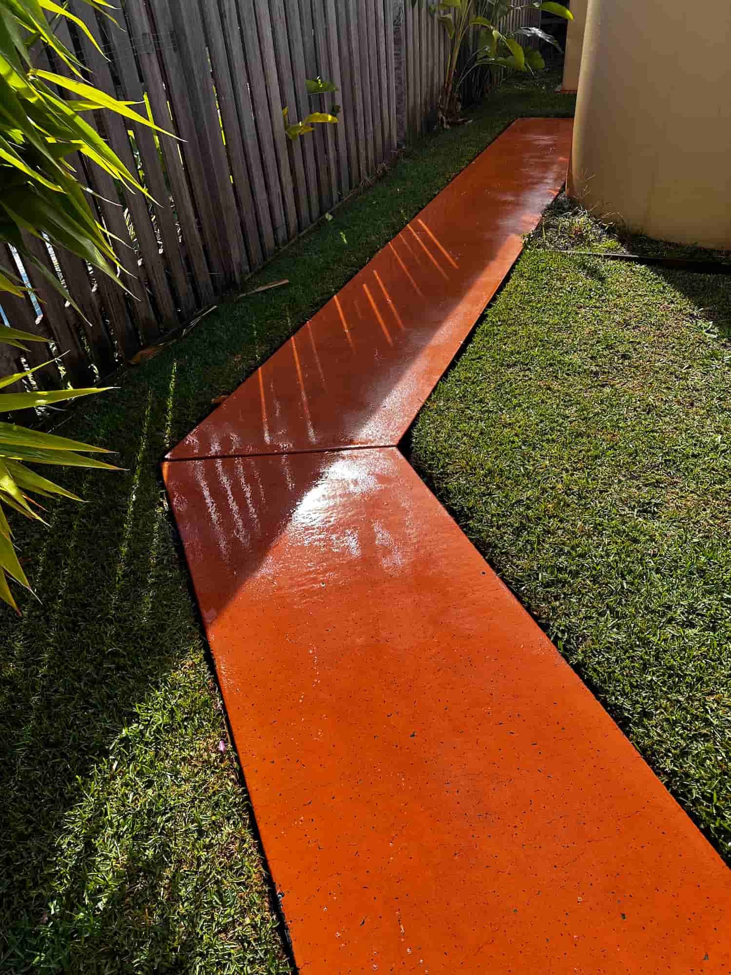 A concrete walkway in a backyard with a wooden fence in the background. — Lighthouse pressure washing in Port Macquarie, NSW
