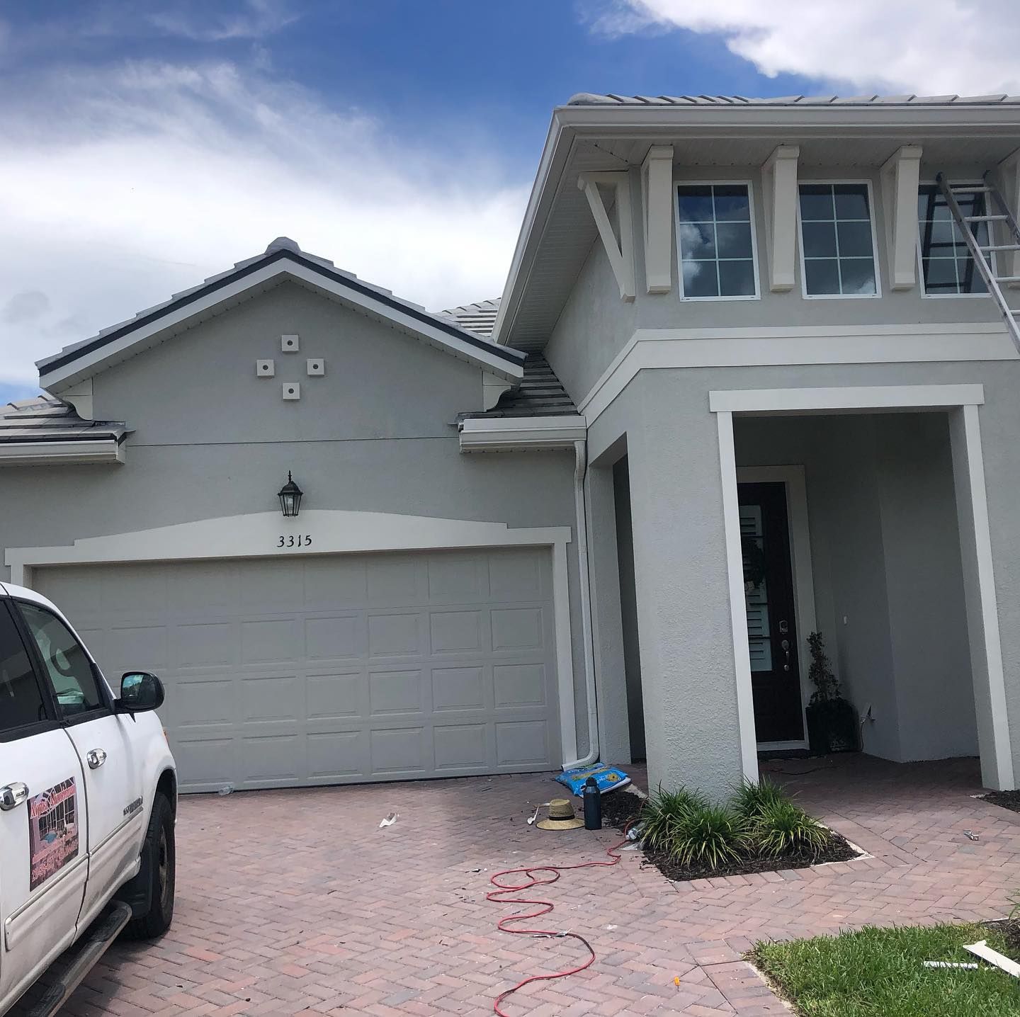 Gray house exterior with painted garage, front door, and truck with painting logo.