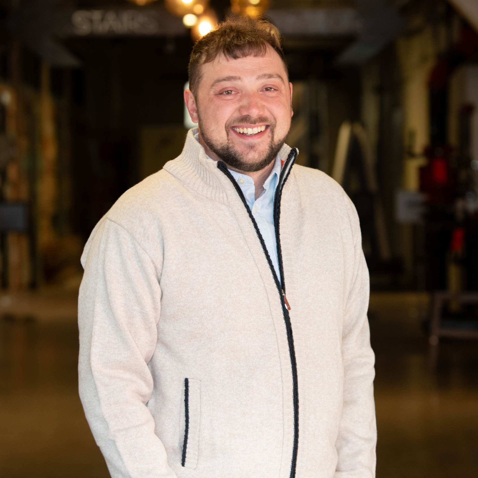 A man is holding a dog in his arms and the dog is wearing a sweater.