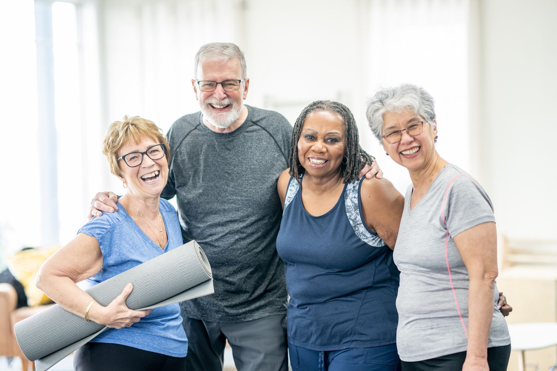 A group of older people are posing for a picture while holding yoga mats.