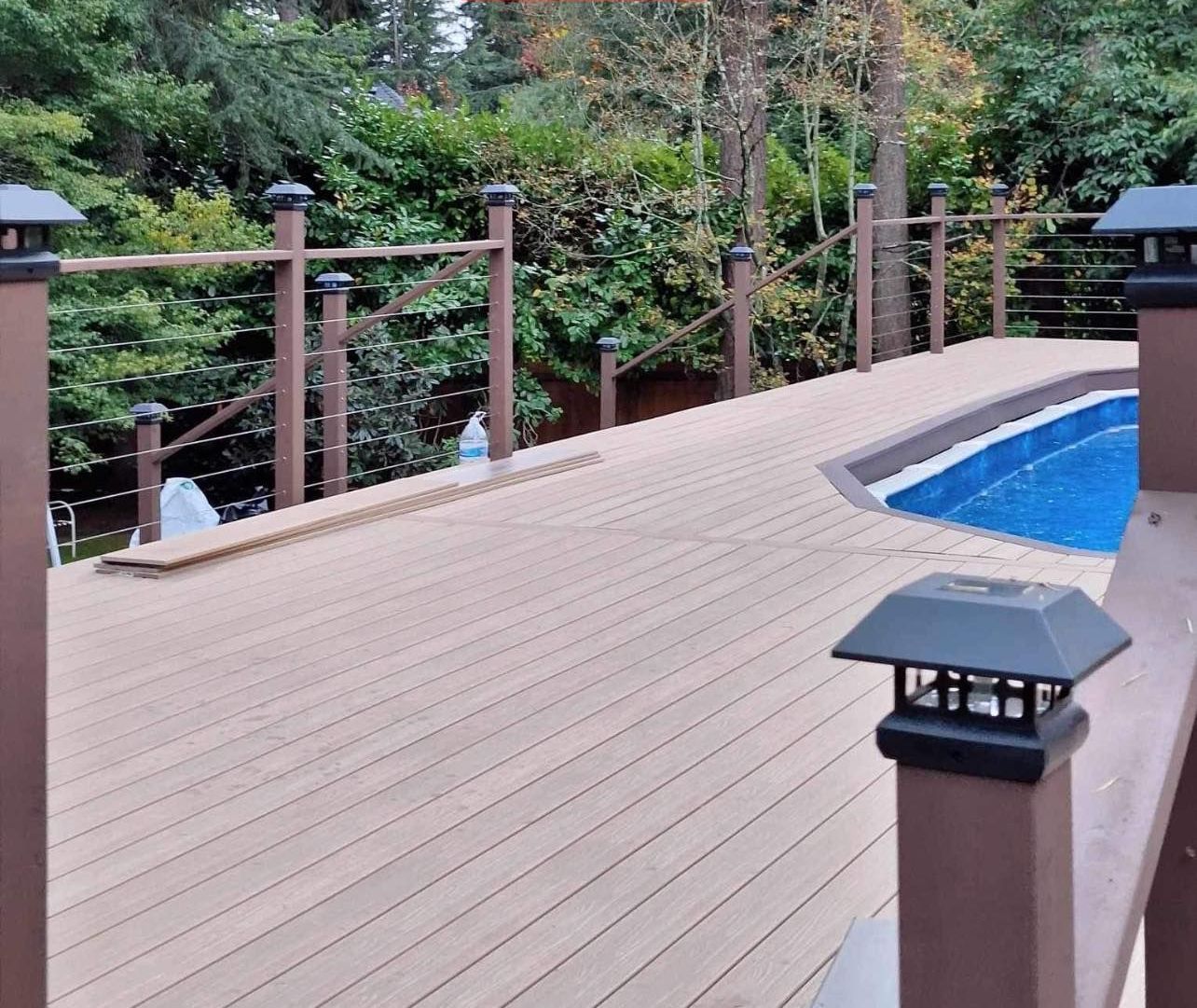 Backyard deck with a spa, next to a building with windows. A doormat is on the ground.