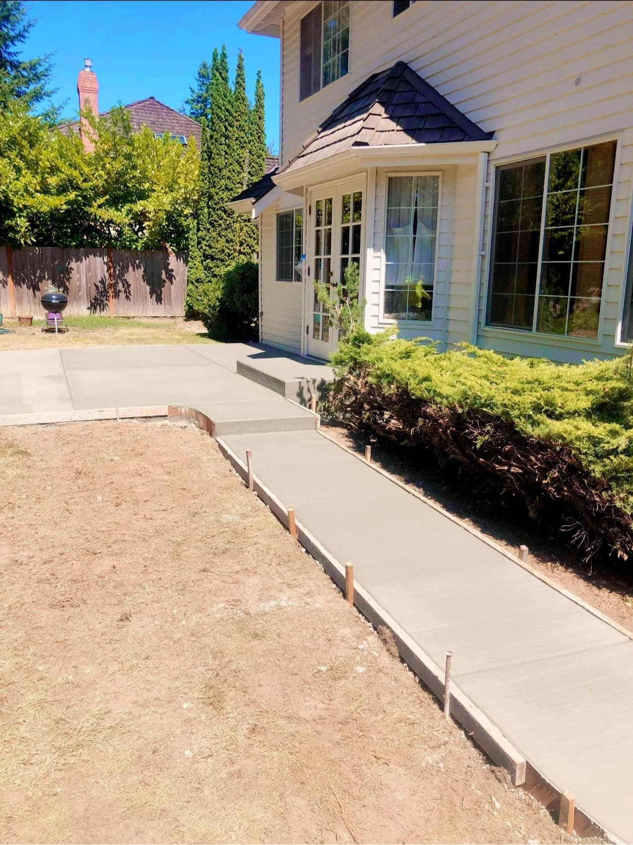 A concrete walkway is being built in front of a house