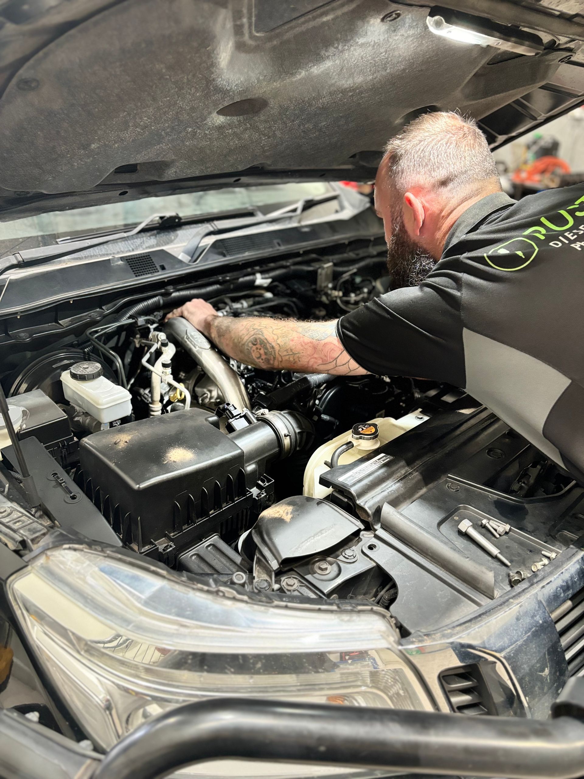 A Man Is Working On A Car Engine— Rusty's Diesel Injection in Browns Plains, QLD
