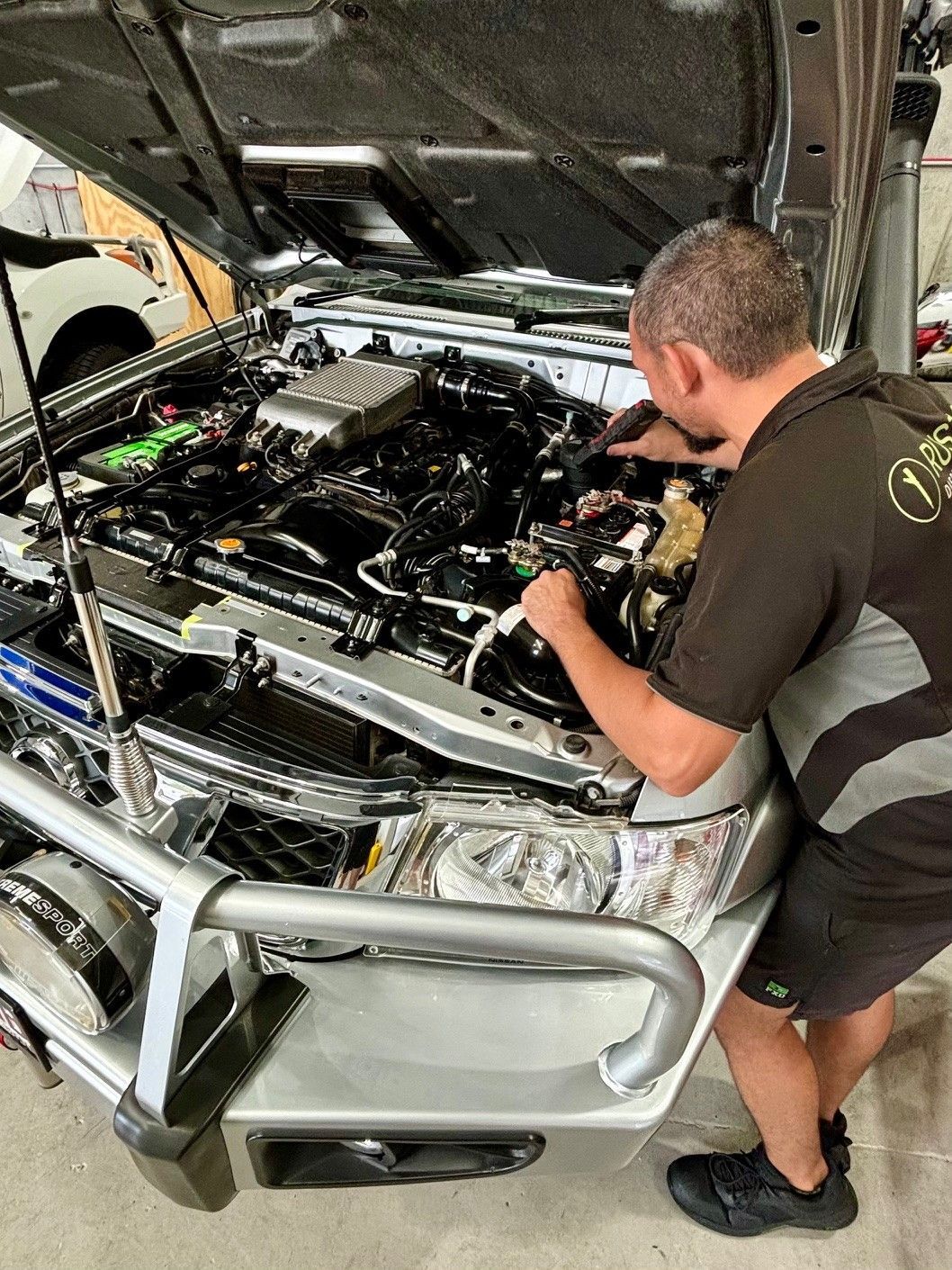 A man is working on the engine of a car in a garage.